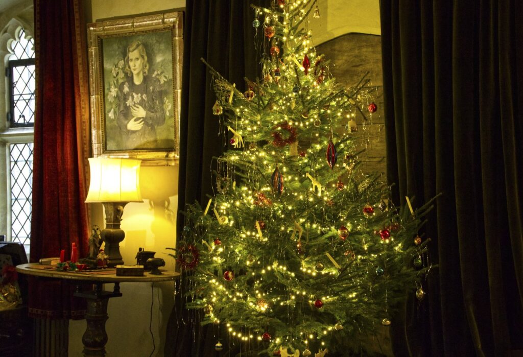 Christmas tree decorated with lights and ornaments in a historic room at Nymans