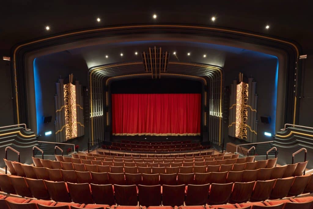 The refurbished Capitol Horsham auditorium with red seating, stage curtains and art deco detailing