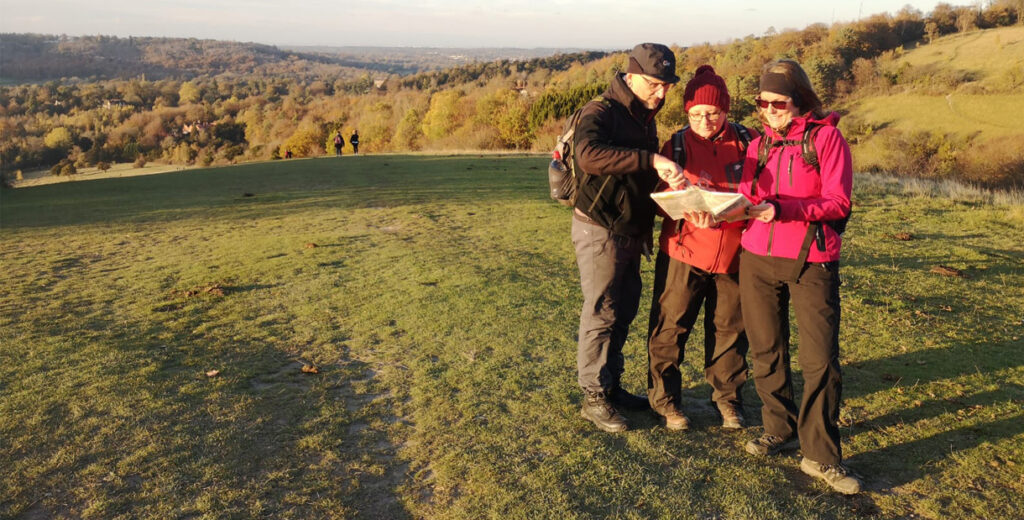 Three walkers studying a map in the countryside on a Pied A Terre Adventures map-reading course