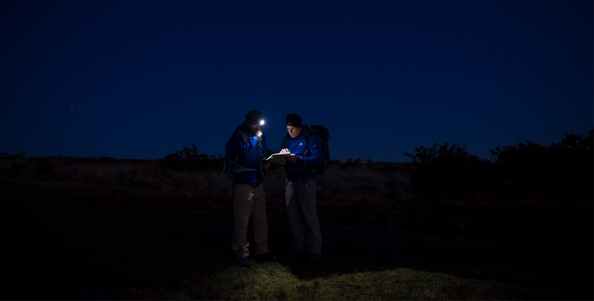 Two walkers studying a map by headtorch during a Pied A Terre Adventures night navigation course