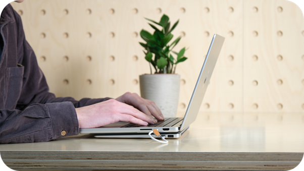 Person using a laptop with the slim Krafted Edge power bank underneath.