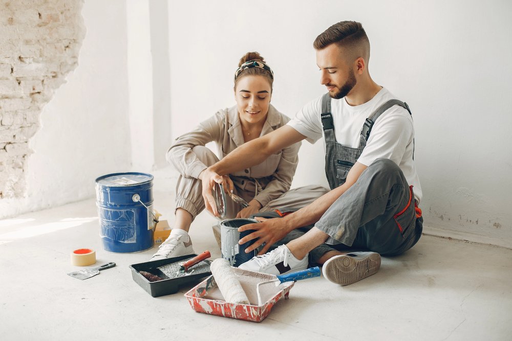 Couple decorating their family home with paint, brushes and rollers
